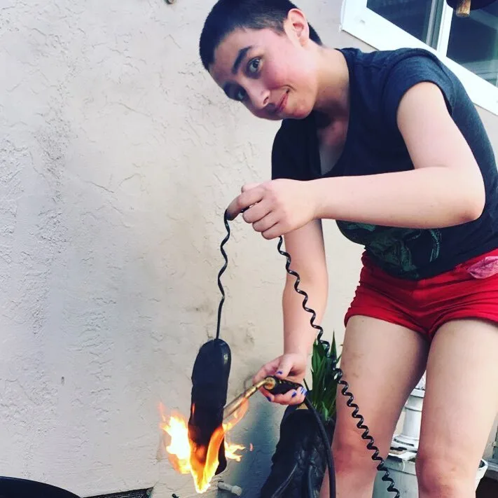 Clover Gardener, age 18, torching a corded telephone to act as a prop for a theatrical performance.